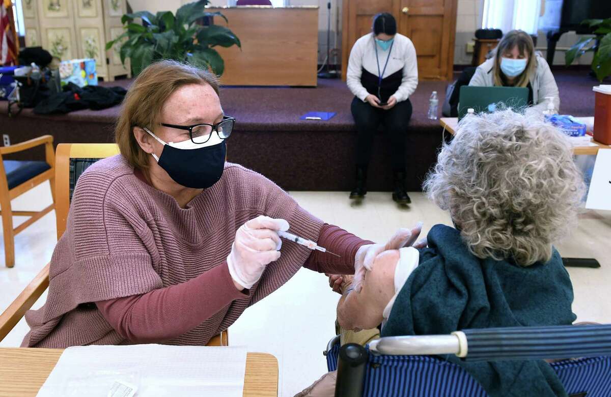 Volunteer Maggie Nuzzelillo, left, a retired Army nurse, gives a shot of the Moderna COVID-19 vaccine to Mary Connelly, 93, of Clinton at the East Haven Senior Center on January 29, 2021.