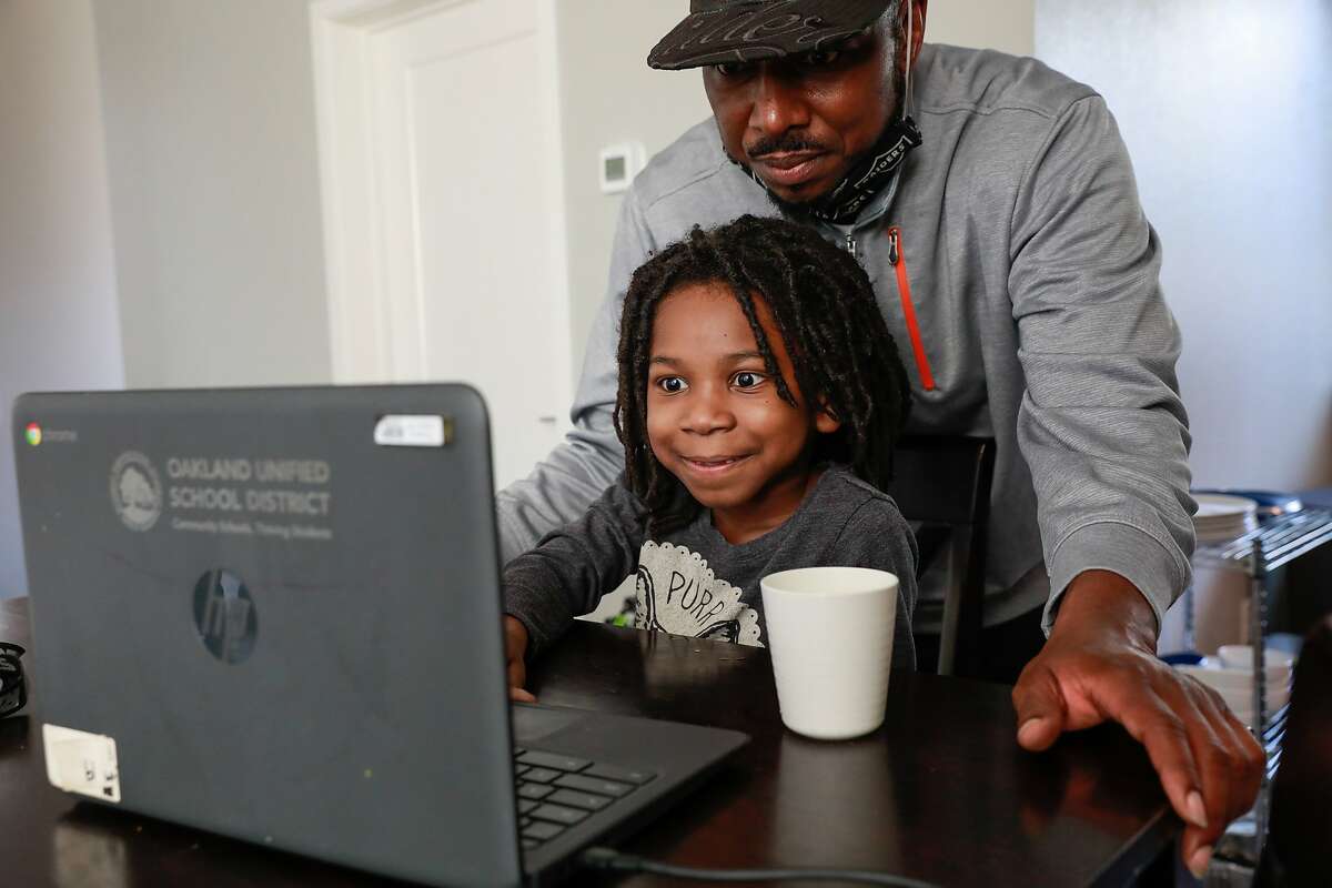 John Jones helps son Josiah, 6, with his virtual learning class at their home in Oakland, California on Friday, Jan. 29, 2021.