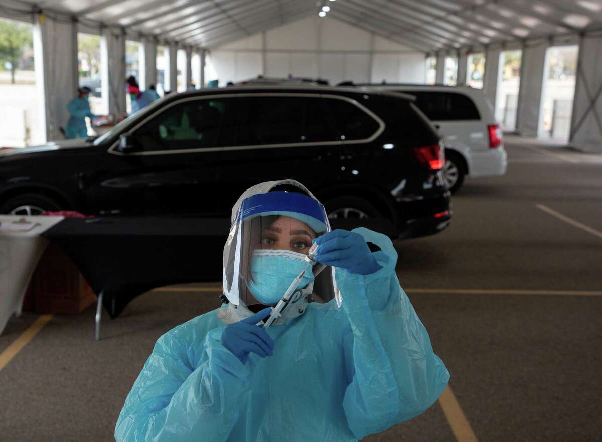 Joyetta Weh prepares a dose of the COVID-19 Moderna vaccine at the drive-through site at Delmar Stadium on Friday, Jan. 29, 2021, in Houston. The site is operated in a partnership between the city and United Memorial Medical Center.