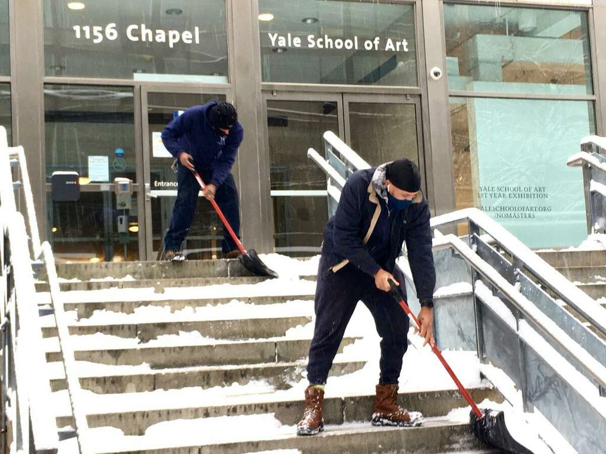 Outside the Yale School of Art Iseman Theater on Chapel Street, Yale University gardener Omar Johnson , right, shovels stairs.