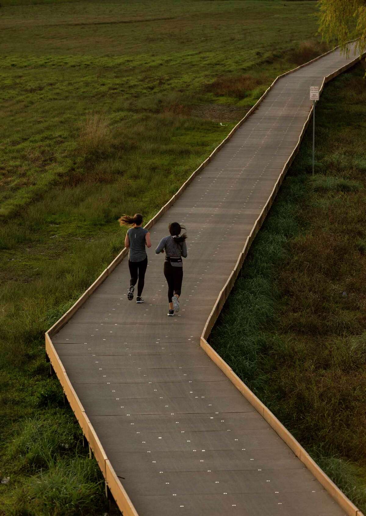 Two joggers enjoy a run along the Salado Creek section of the Howard W. Peak Greenway Trail System.