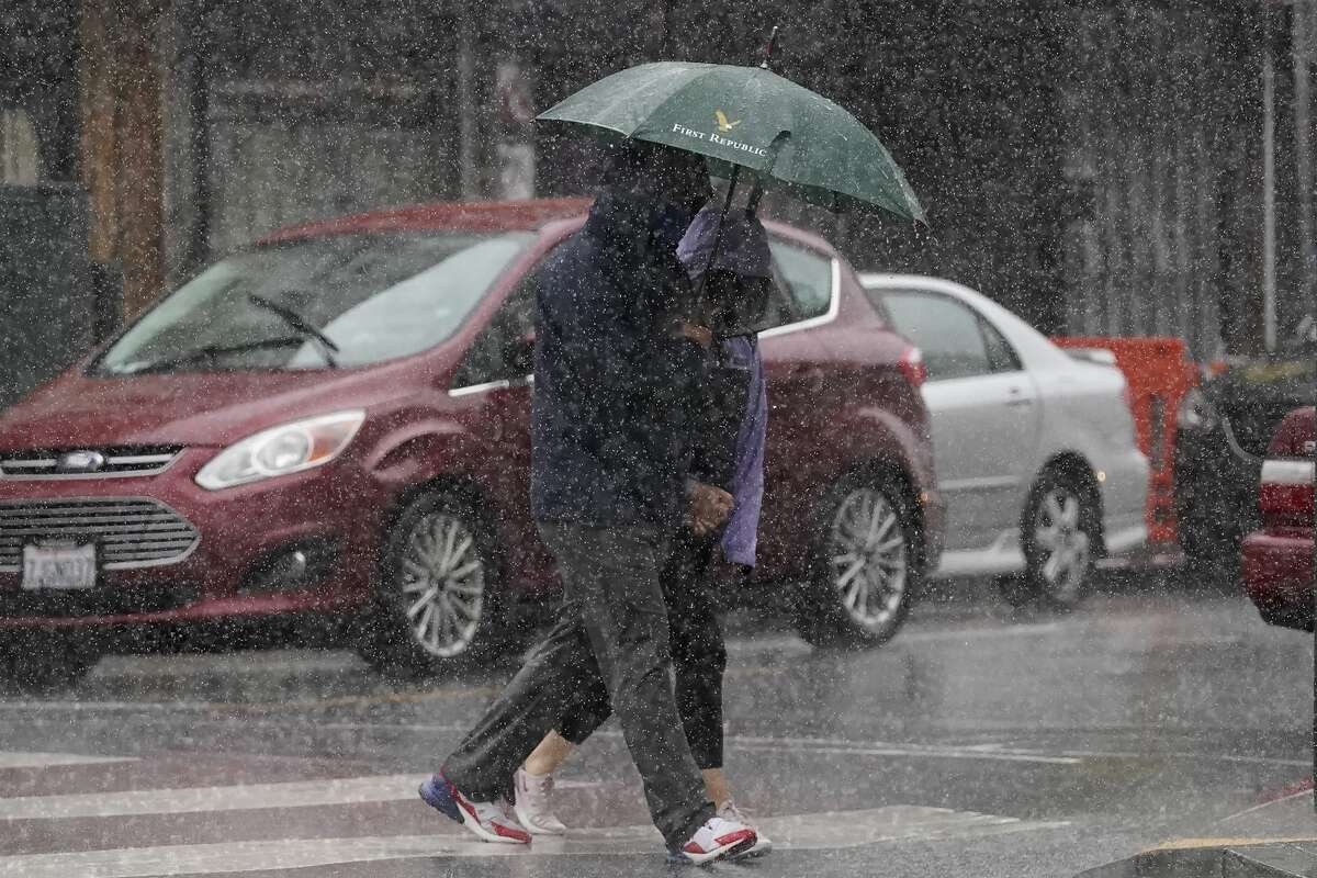 People carry an umbrella while walking in the rain in San Francisco, Sunday, Dec. 13, 2020.