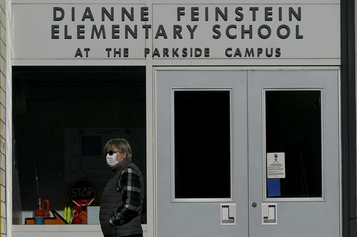 A pedestrian walks below a sign for Dianne Feinstein Elementary School in San Francisco.