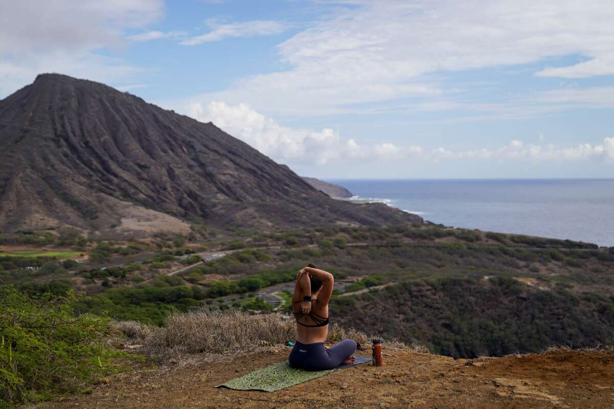 FILE: From a hiking trail overlooking Hanauma Bay, Jessica Linster, 24, of Kahala, stretches after morning yoga on Oct. 18, 2020 in Hawaii.