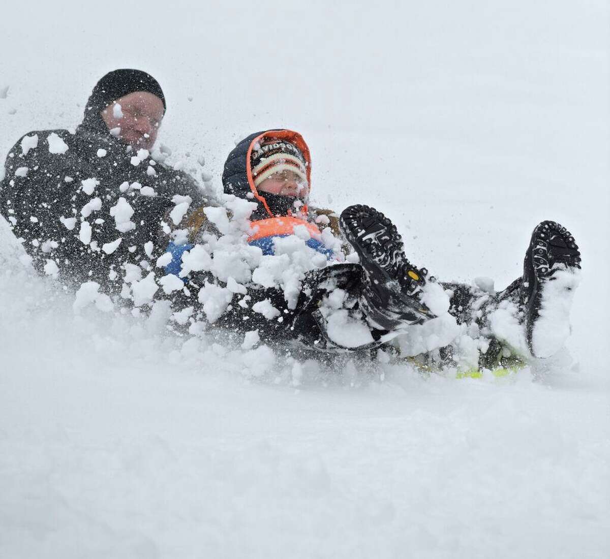 Mason Kis, of Danbury, and his father Peter get a face full of snow as they sled down a hill on the first hole of Richter Park Golf Course after another snowstorm hits greater Danbury, Conn. Tuesday, March 13, 2018.