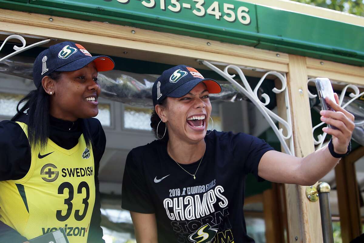 Seattle Storm forward Alysha Clark, right, holds her phone as she and Noelle Quinn, left, take part in a parade to celebrate the Storm winning the 2018 WNBA basketball championship, Sunday, Sept. 16, 2018, in Seattle. (Genna Martin, seattlepi.com)
