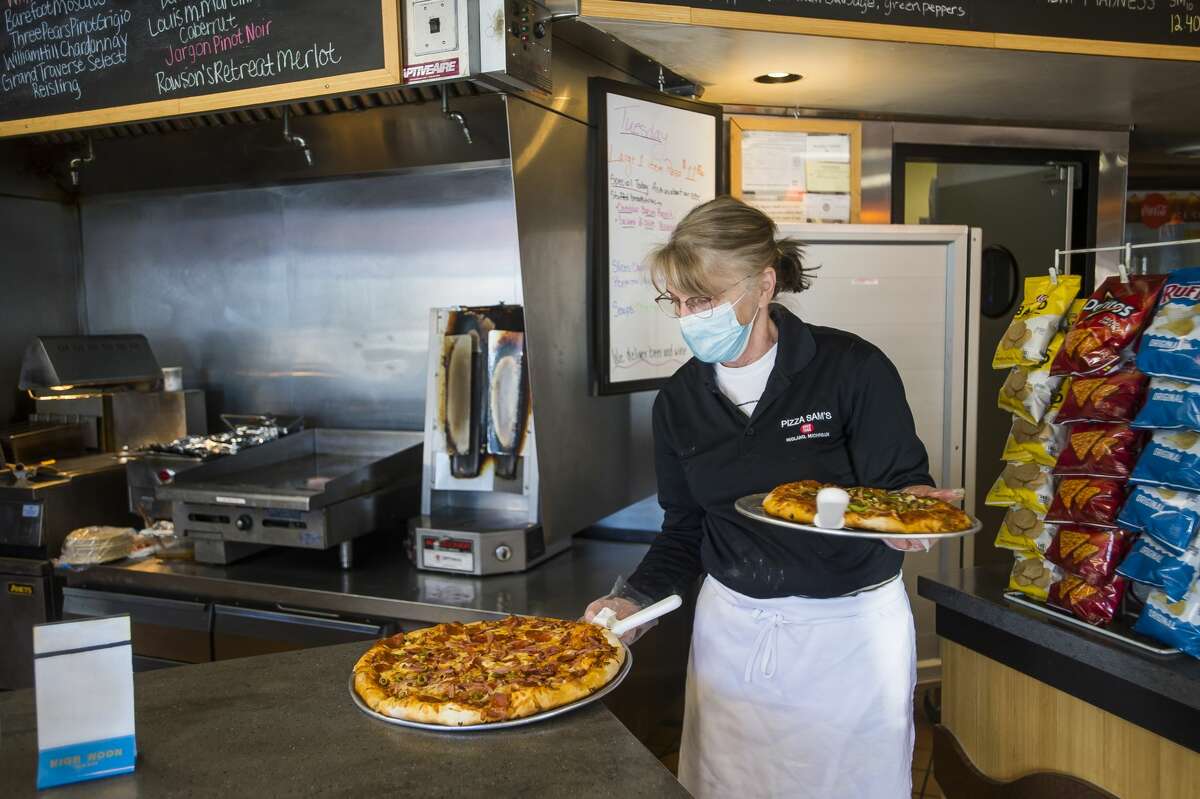 Dawn Rugenstein carries two pizzas to a table during the lunch rush Tuesday, Feb. 2, 2021 at Pizza Sam's in downtown Midland. (Katy Kildee/kkildee@mdn.net)