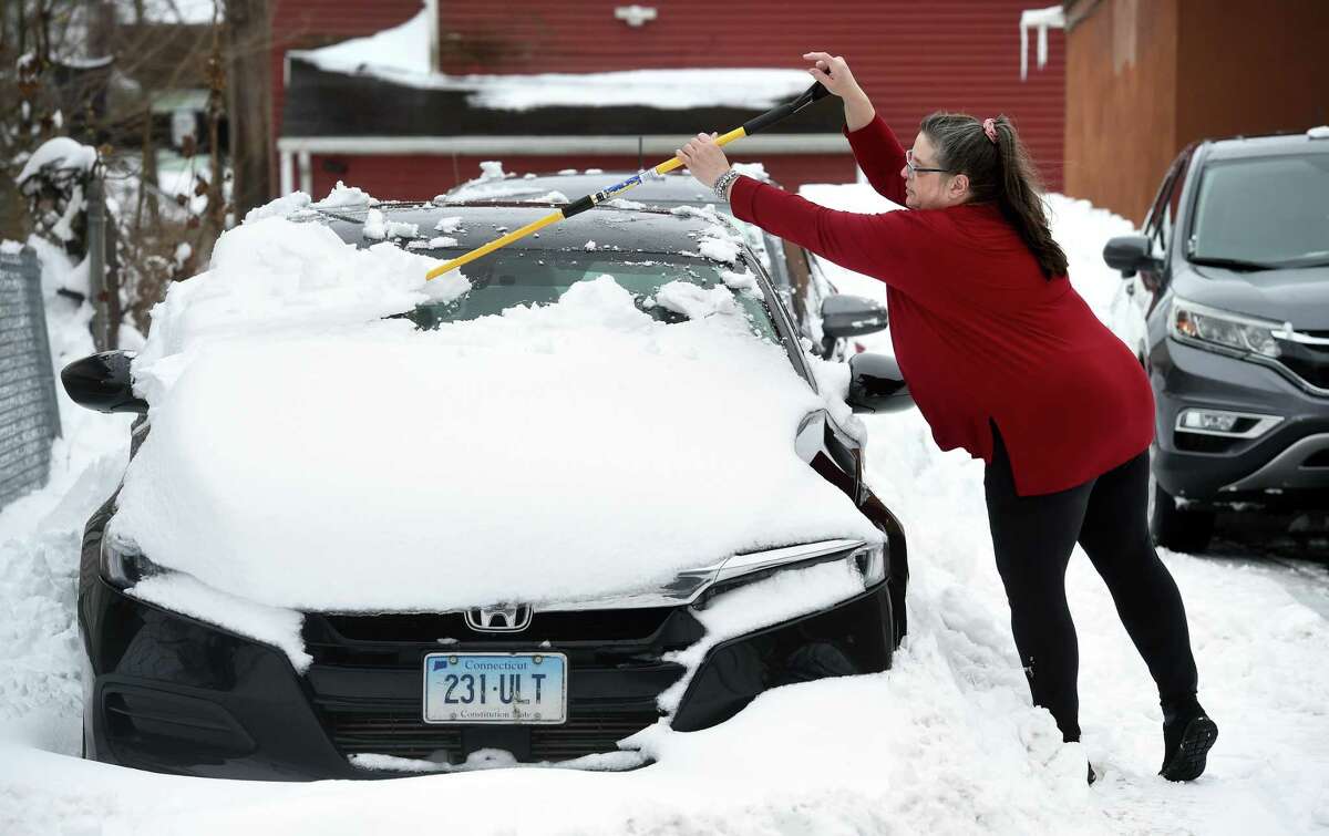 Kathy Radin clears snow from her nephew's car in Ansonia on February 2, 2021.