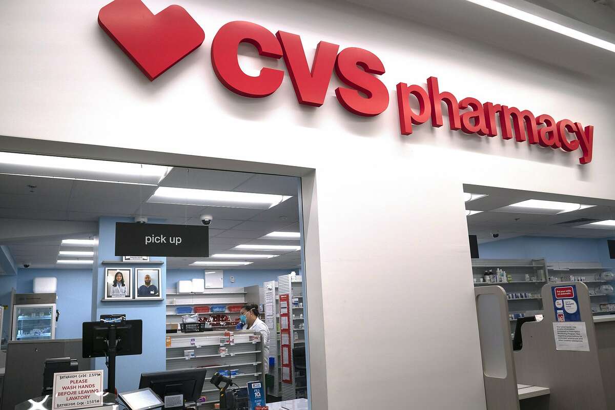 FILE - In this March 17, 2020, file photo, Pharmacist Evelyn Kim, wears a mask and gloves at the CVS pharmacy at Target in the Tenleytown area of Washington. The Biden administration will begin providing COVID-19 vaccines to U.S. pharmacies, including CVS, part of its plan to ramp up vaccinations as new and potentially more serious virus strains are starting to appear. (AP Photo/Carolyn Kaster)