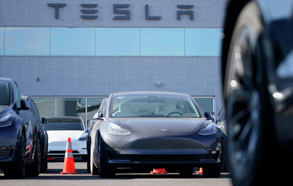 A long line of unsold 2021 Model 3 sedans sits at a Tesla dealership Sunday, Jan. 24, 2021, in Littleton, Colo. (AP Photo/David Zalubowski)