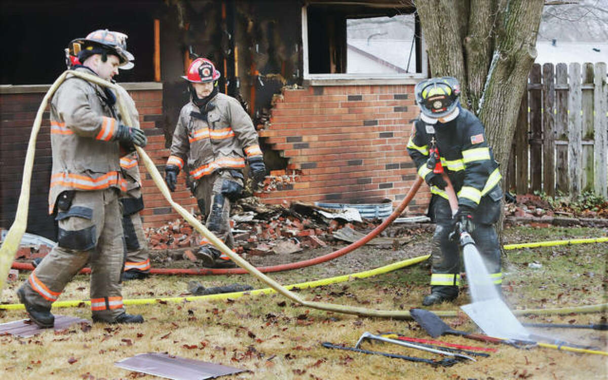 A firefighter washes equipment Monday morning after a fire at a home in the 2300 block of Wedgewood Avenue in Godfrey that left two people dead, Robert B. Andrews, 59, and Leonard “James” Ebrey, 67. Police believe the two died in a double homicide.