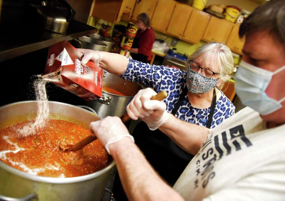 Judy Holko-Piro adds salt as Jack Dobrucky stirs a pot of creole pasta sauce in the kitchen at St. Paul Lutheran Church in the Byram section of Greenwich, Conn. Thursday, Jan. 28, 2021. The spaghetti creole dish was a staple at Greenwich High School in the 1960s, '70s, and '80s and the church recreates the nostalgic dish every year to serve to congregants and locals.