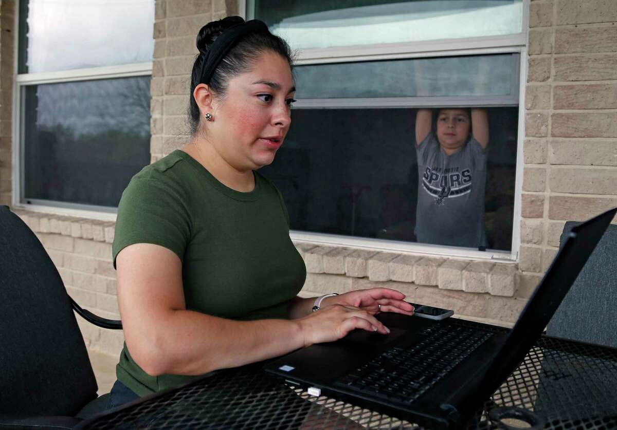 Amanda Flores attends the SA Virtual School Fair on Saturday to research possible schools for her child, Jaxson Flores, 6 as he looks through the window at her home.