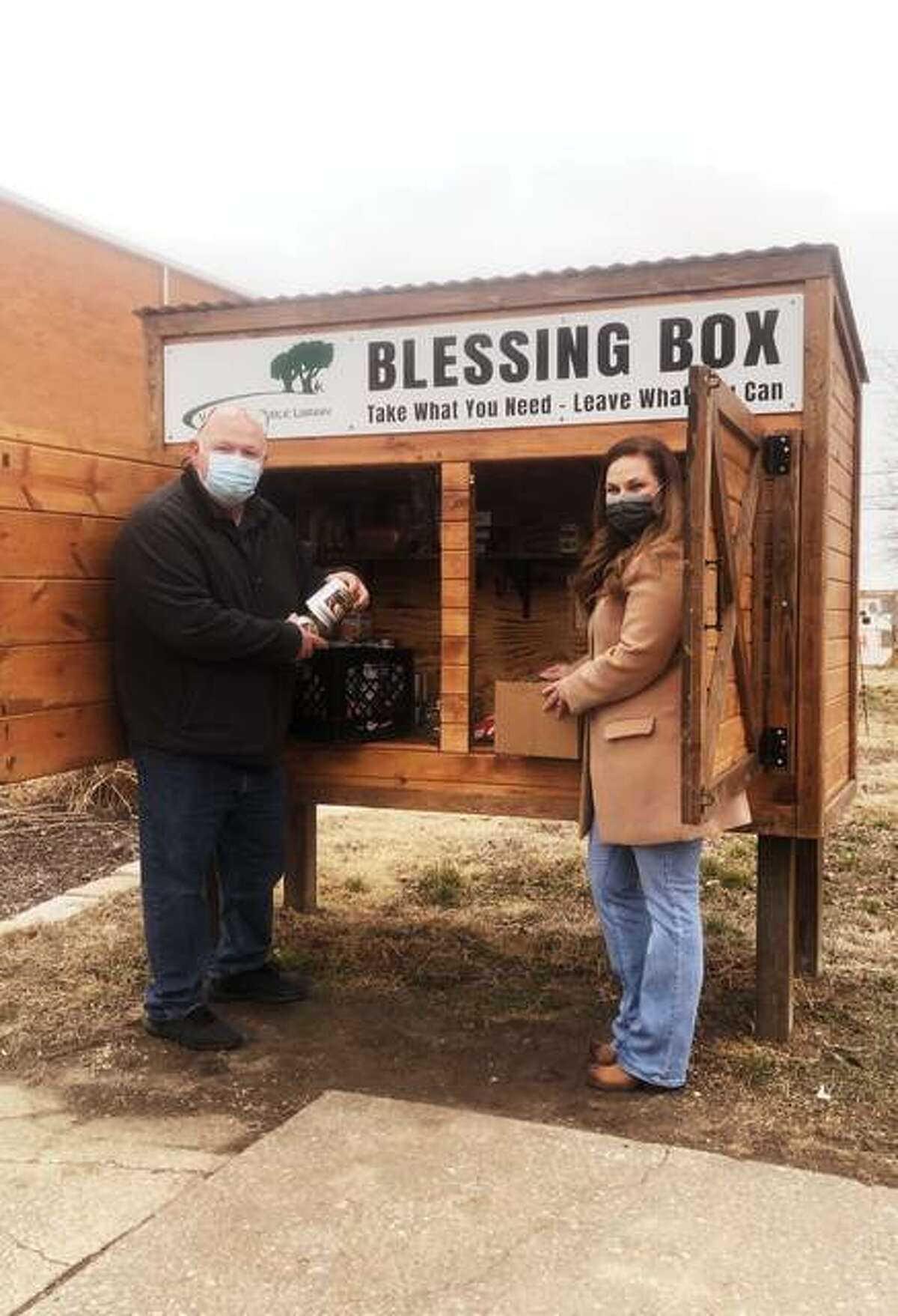 Wood River Councilman Mike Anderson, left, and state Sen. Rachelle Crowe take canned goods to the Wood River Public Library’s Blessing Box.