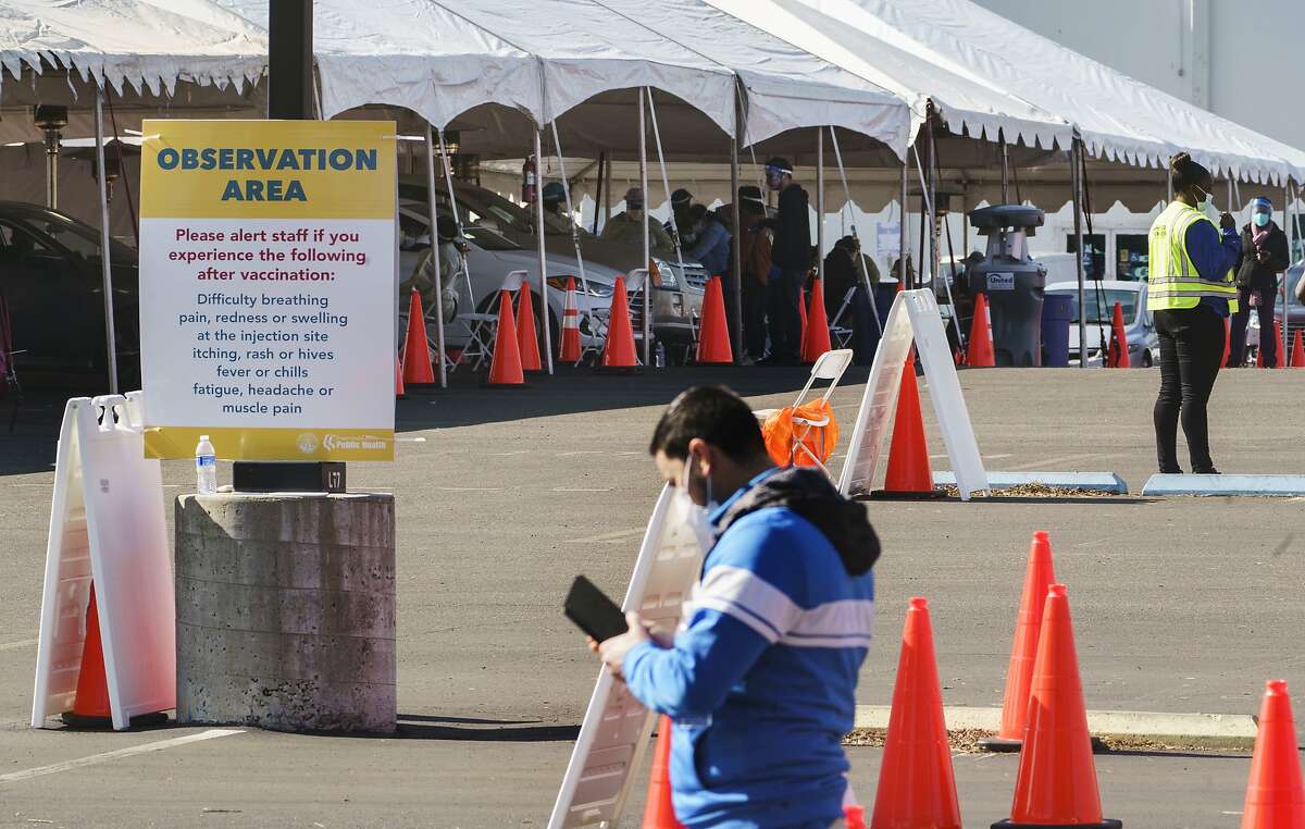 Health workers at an "Observation Area" wait for motorists being inoculated with a COVID-19 vaccine at the mass vaccination site at the parking lot of L.A. County Office of Education headquarters in Downey, Calif., Wednesday, Feb. 3, 2021. Currently, the state has authorized health workers, teachers, food and agriculture employees, other first responders and people 65 and older to be inoculated. (AP Photo/Damian Dovarganes)