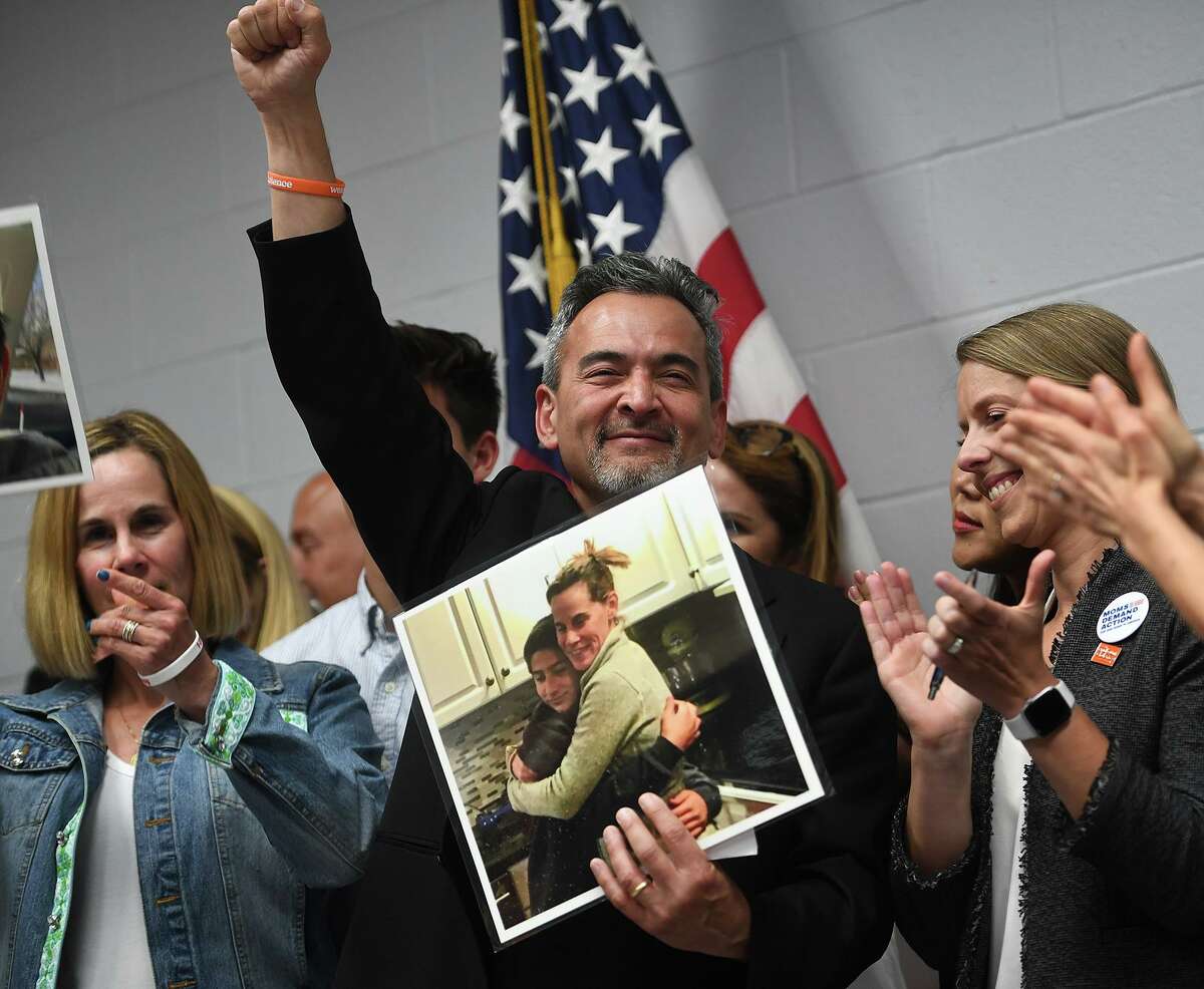Standing with his wife Kristen, Michael Song, of Guilford, raises his fist in the air following the signing of Ethan's Law by Governor Ned Lamont in a ceremony at the Guilford Fire Department on Thursday, June 13, 2019. The Songs' son Ethan, 15, fatally shot himself with an unsecured gun in January of 2018.