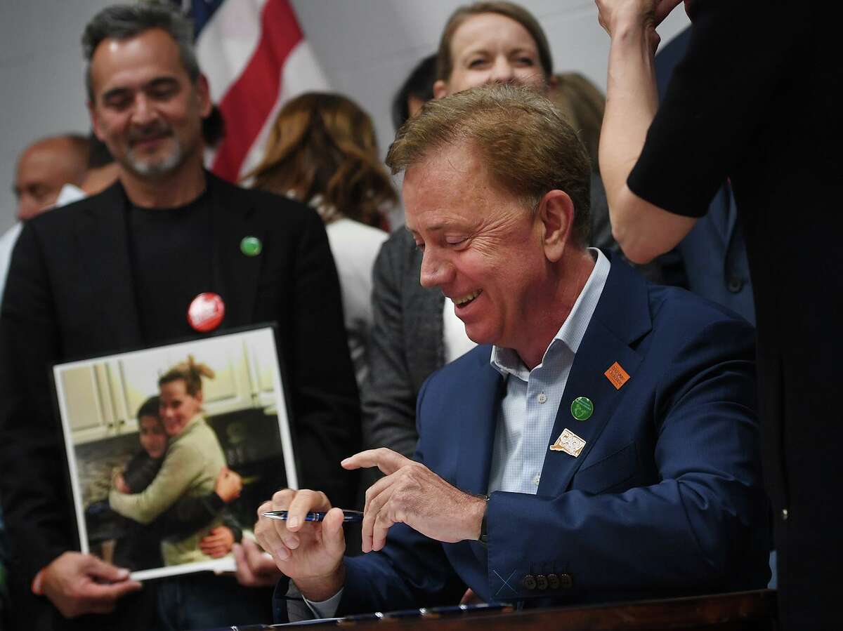 Michael Song, left, of Guilford, looks on as Governor Ned Lamont signs Ethan's Law in a ceremony at the Guilford Fire Department on Thursday, June 13, 2019. The Songs' son Ethan, 15, fatally shot himself with an unsecured gun in January of 2018.