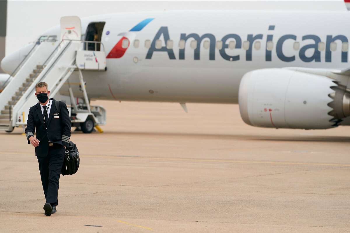 (FILES) In this file photo taken on December 2, 2020 an exterior view of an American Airlines B737 MAX airplane is seen as a man walks at Dallas-Forth Worth International Airport in Dallas, Texas. - American Airlines will notify 13,000 workers that they could be laid off due the prolonged industry downturn caused by the Covid-19 pandemic, the carrier said on February 3, 2021. (Photo by Cooper NEILL / AFP) (Photo by COOPER NEILL/AFP via Getty Images)