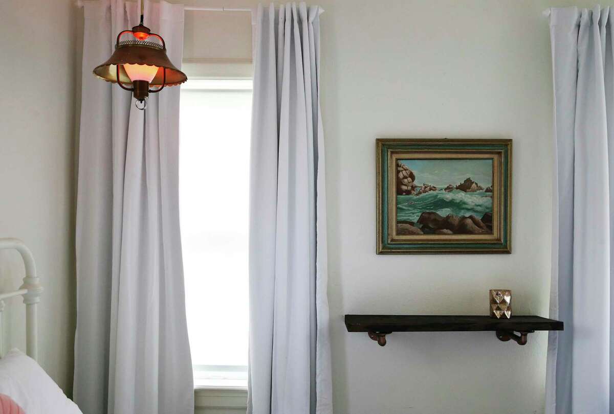 Some of the beach house decor includes canvas curtains and seascape artwork in this bedroom in the second-floor unit.