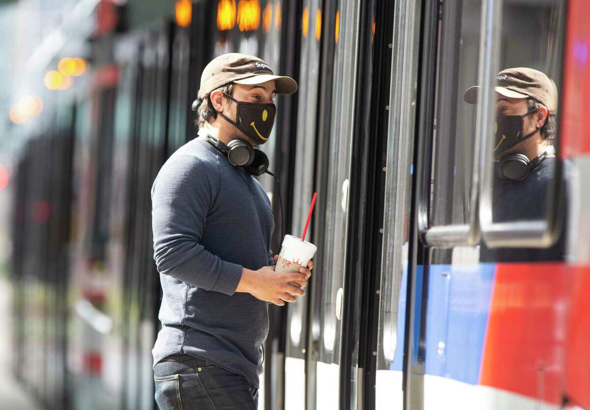 A Metropolitan Transit Authority rail passenger boards a train at the Main Street Square station on Feb. 3, 2021, in downtown Houston. Since June when masks became required on transit, Metro has handed out 2 million masks. That's expected to continue as a federal requirement for mask use kicked in earlier this week.