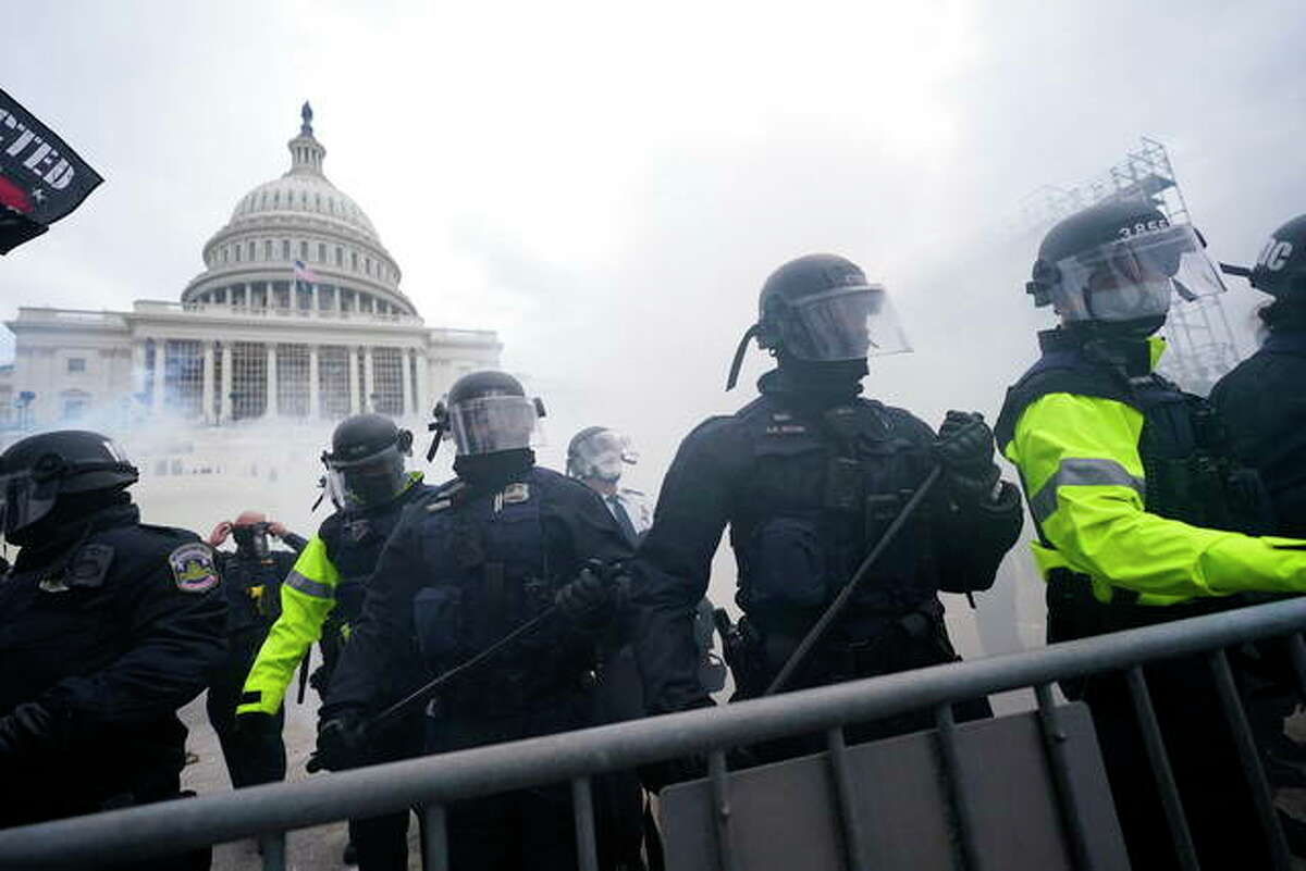 Police stand guard after holding off rioters who tried to break through a police barrier at the Capitol in Washington, D.C., in January. As federal officials grapple with how to confront the national security threat from domestic extremists after the deadly siege of the Capitol, civil rights groups and communities of color are watching warily for any moves to expand law enforcement power or authority.