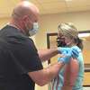 Caroline Hennigan receives the first injection of the Moderna COVID-19 vaccine from Brian Cross, RN, with Aurora Concepts.