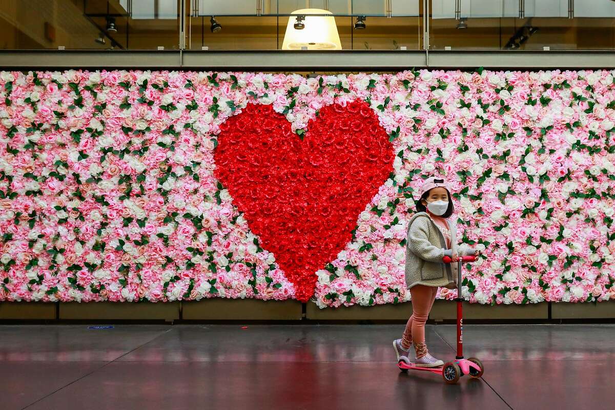 Olivia Kim, 5, (center) scoots past a floral Valentine's Day themed backdrop set up at the Ferry Building on Thursday, Feb. 4, 2021 in San Francisco, California.