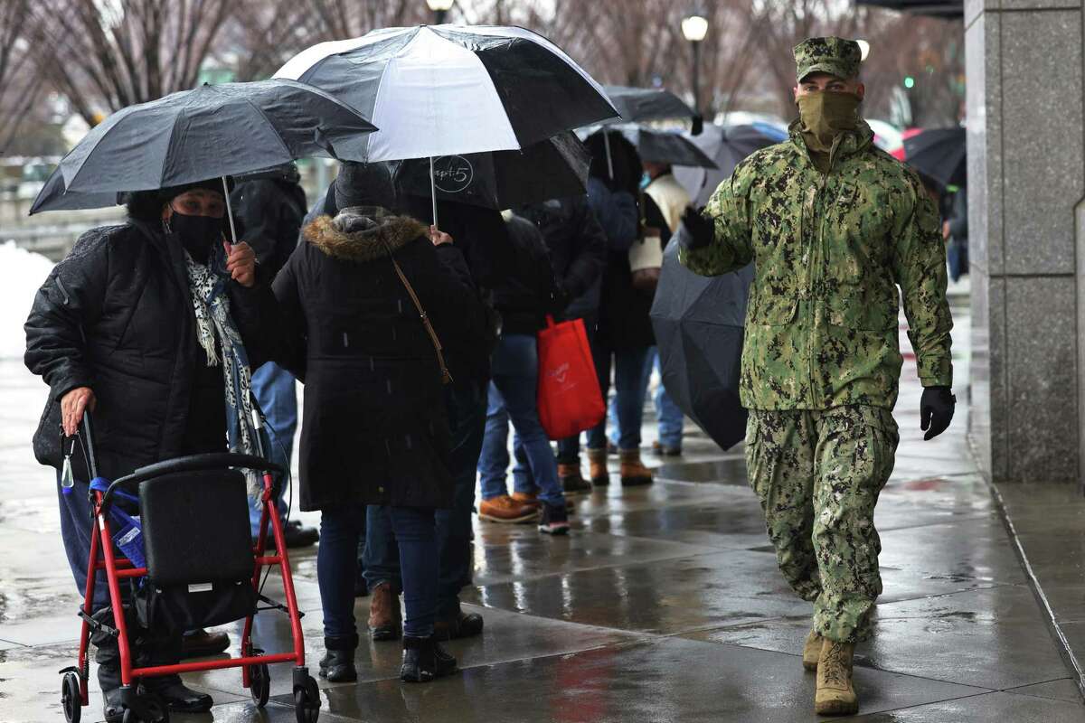 A National Guard soldier helps to enforce social distancing as people wait in line to enter the coronavirus (COVID-19) vaccination site at Yankee Stadium in New York on Friday.