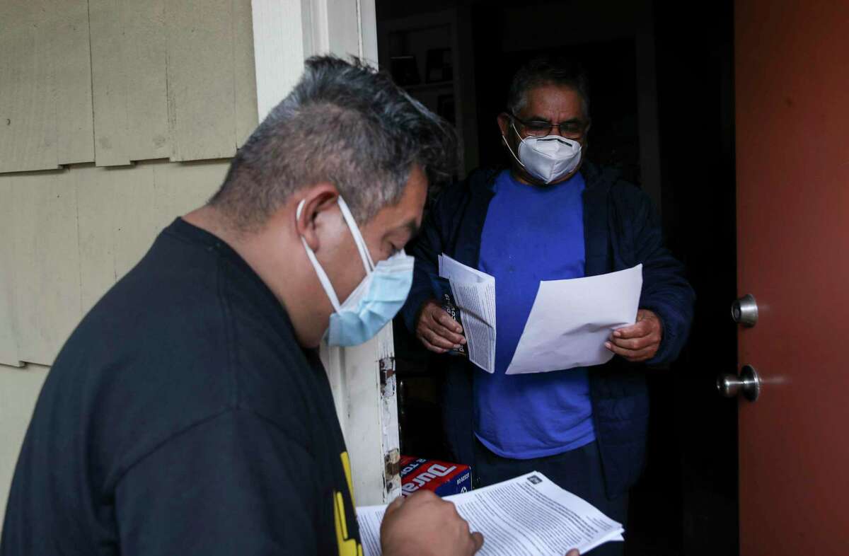 Adan Aurioles, right, talks with Alain Cisneros, an activist with FIEL Houston, about his rights as a tenant related to eviction proceedings Thursday, Feb. 4, 2021, at the Redford Apartments in Houston. Aurioles said he is 66, and that he has been without work for three months. Cisneros and another man from FIEL Houston distributed fliers with information at the apartment complex.