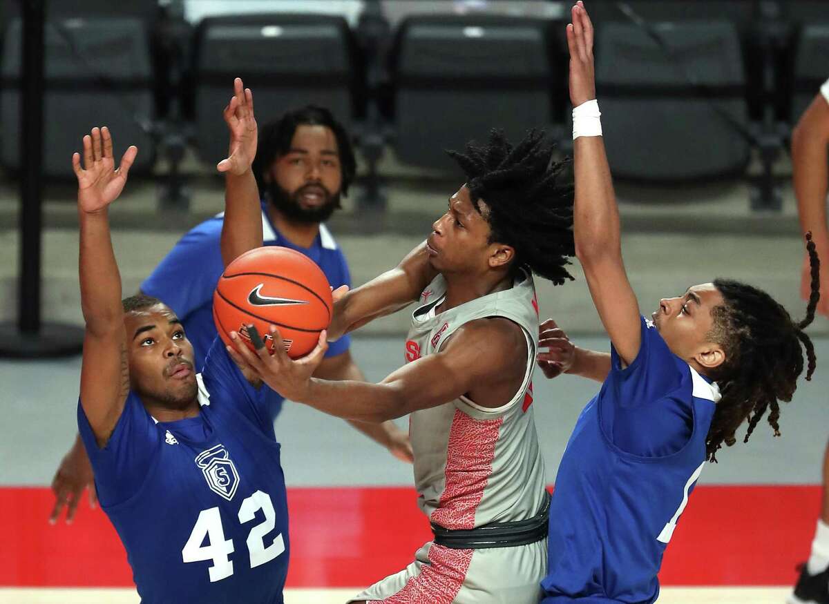 Houston guard Tramon Mark, center, drives to the basket against Our Lady of the Lakeguard Cameron Fields (42) and guard Xavier Woodington, right, during the second half on a NCAA basketball game at Fertitta Center Saturday, Feb. 6, 2021, in Houston. UH won the game 112-46.