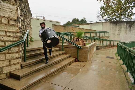 James Gemino, a New York native who recently moved to San Antonio, carries a drum kit down the steps near the Josephine Street bridge on a rainy Sunday afternoon.