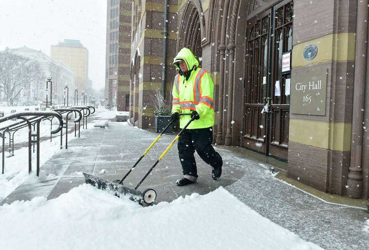 New Haven, Connecticut - Sunday, February 07, 2021: Vidal Santos, and employee of Perco Inc., a landscaping management company, clears snow Sunday from the steps of New Haven City Hall.