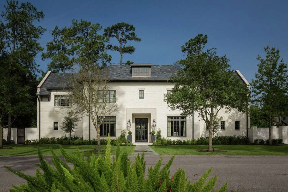 This Houston home built by Thompson Custom Homes was built with a painted brick exterior. Its brick was painted white and paired with a dark roof and steel-framed windows and doors.