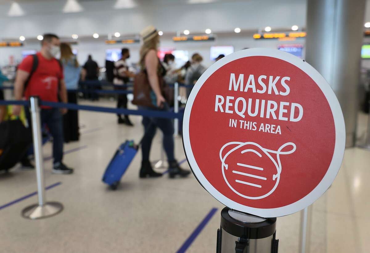 FILE: A sign reading, 'masks required in this area,' is seen as travelers prepare to check-in for their Delta Airlines flight at the Miami International Airport on February 01, 2021.