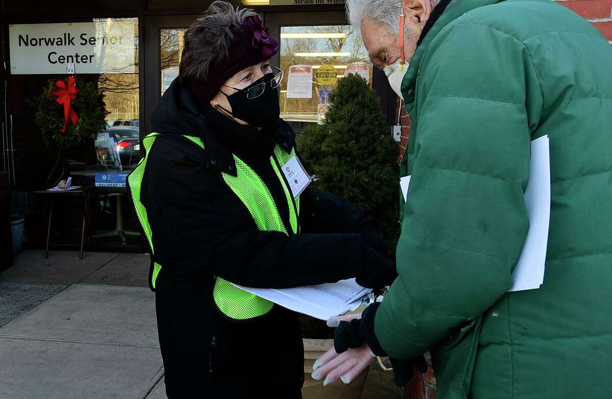 Volunteer Donna Schlegel helps local residents line up for their COVID vaccine Jan.30, at the Norwalk Senior Center in Norwalk.