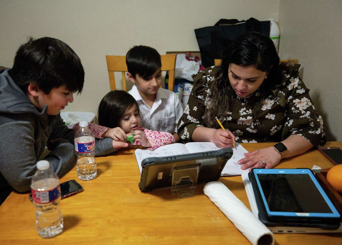 Manuel, left, and his sister Camila, 4, watch as their mother Vanessa Rodriguez, right, helps her 9-year-old son Giovanny, center, with math home work after eating dinner in their home Wednesday, Feb. 3, 2021, in Crosby, Texas. Rodriguez, from Mexico, has been thinking about applying for DACA for many years, but it wasn't until president Joe Biden took office that she finally felt safe to do so. As a mother of three American children, she was afraid of giving her information to the government and being deported. Now she and her husband are among the many DACA eligible people that are applying for the first time.