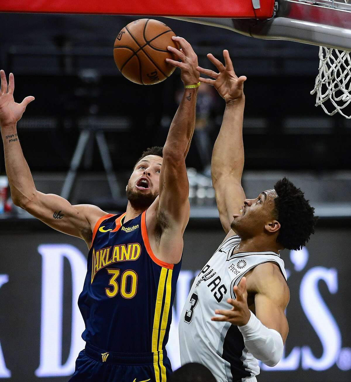 Stephen Curry (30) of the Golden State Warriors battles Keldon Johnson (3) of the San Antonio Spurs for a rebound during first-half NBA action in the AT&T Center on Monday, Feb. 8, 2021.
