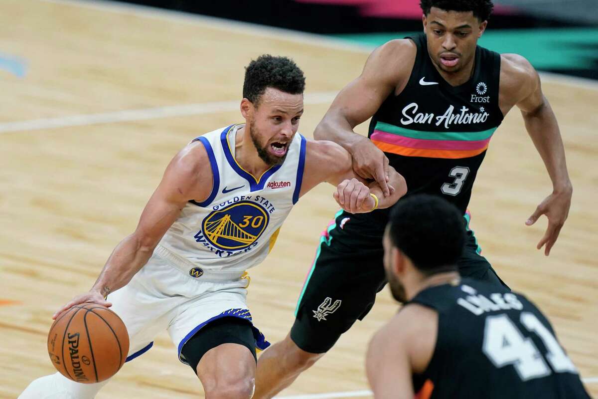 Golden State Warriors guard Stephen Curry (30) drives past San Antonio Spurs forward Keldon Johnson (3) during the second half of an NBA basketball game in San Antonio, Tuesday, Feb. 9, 2021. (AP Photo/Eric Gay)