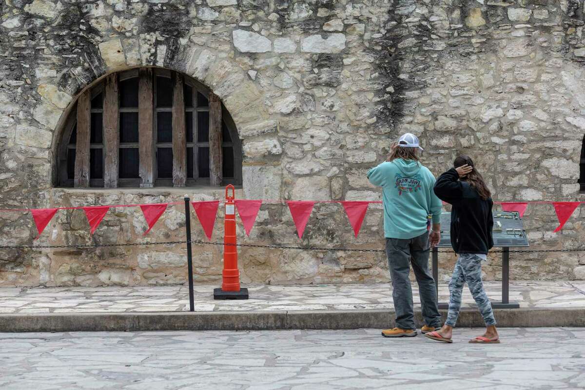 People walk Monday, Feb. 8, 2021 in front of the west wall of the Alamo Long Barracks. Conservators at the Alamo are preparing to clean the west and south walls of the long barracks, one of the oldest structures in San Antonio, to assess the state of the building's rock and mortar.