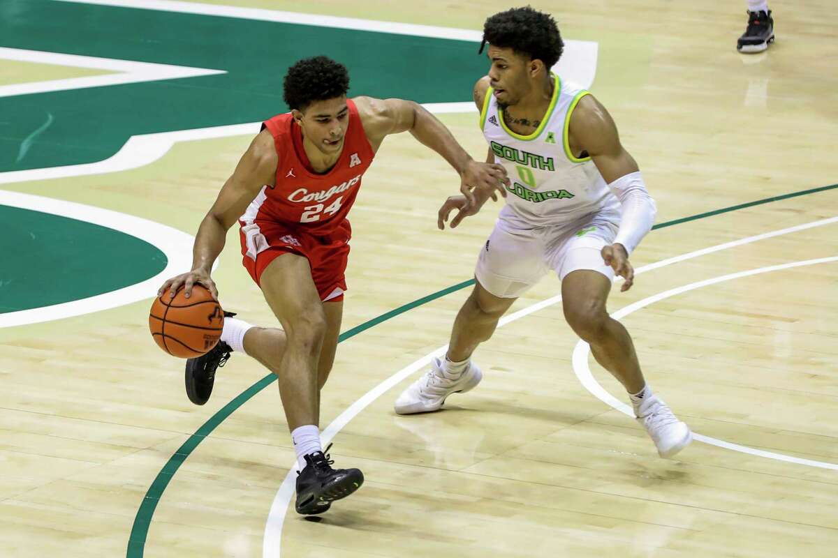 Houston's Quentin Grimes, left, drives past South Florida's David Collins during the first half of an NCAA college basketball game Wednesday, Feb. 10, 2021, in Tampa, Fla. (AP Photo/Mike Carlson)