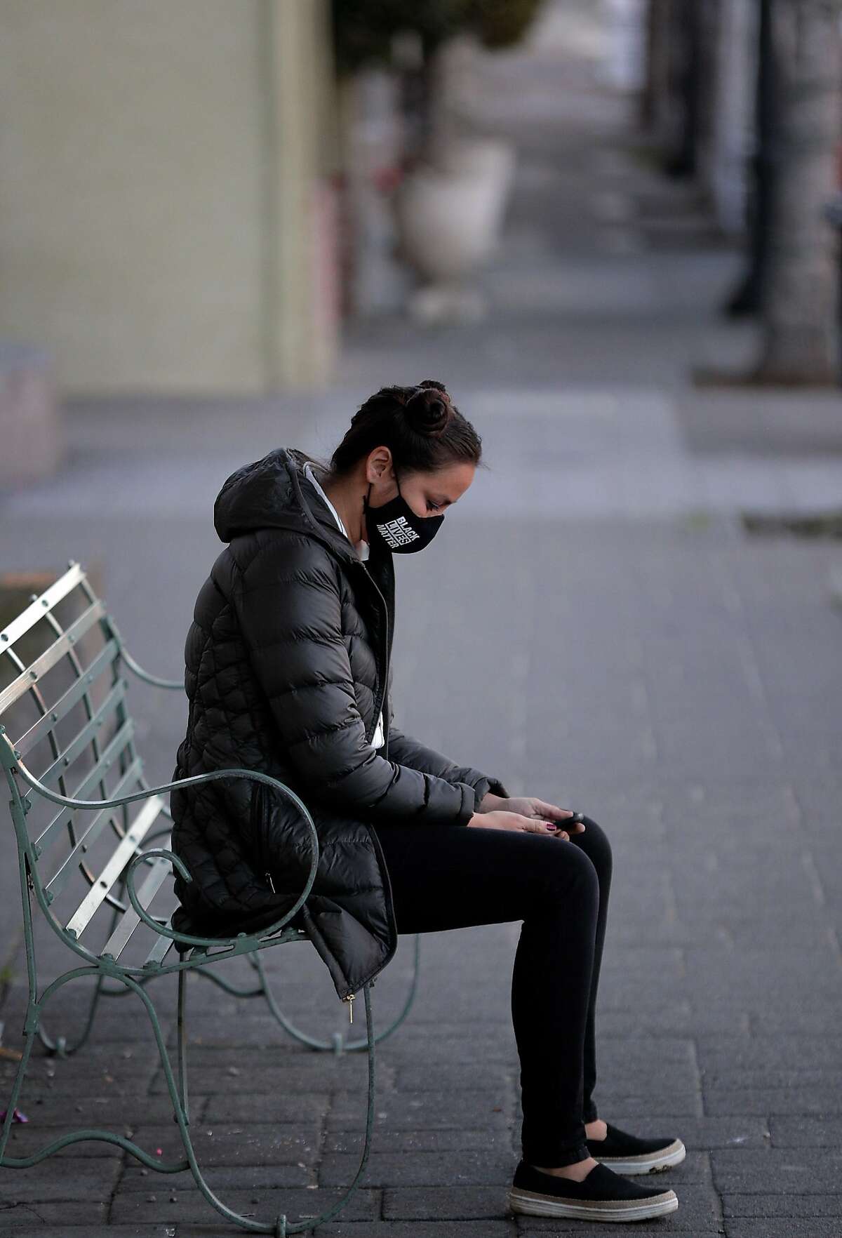 Kimi Stout sits on a bench in Petaluma with her Black Lives Matter face mask. Months after quitting her job at the Girl & the Fig, she now works as a part-time sales associate.