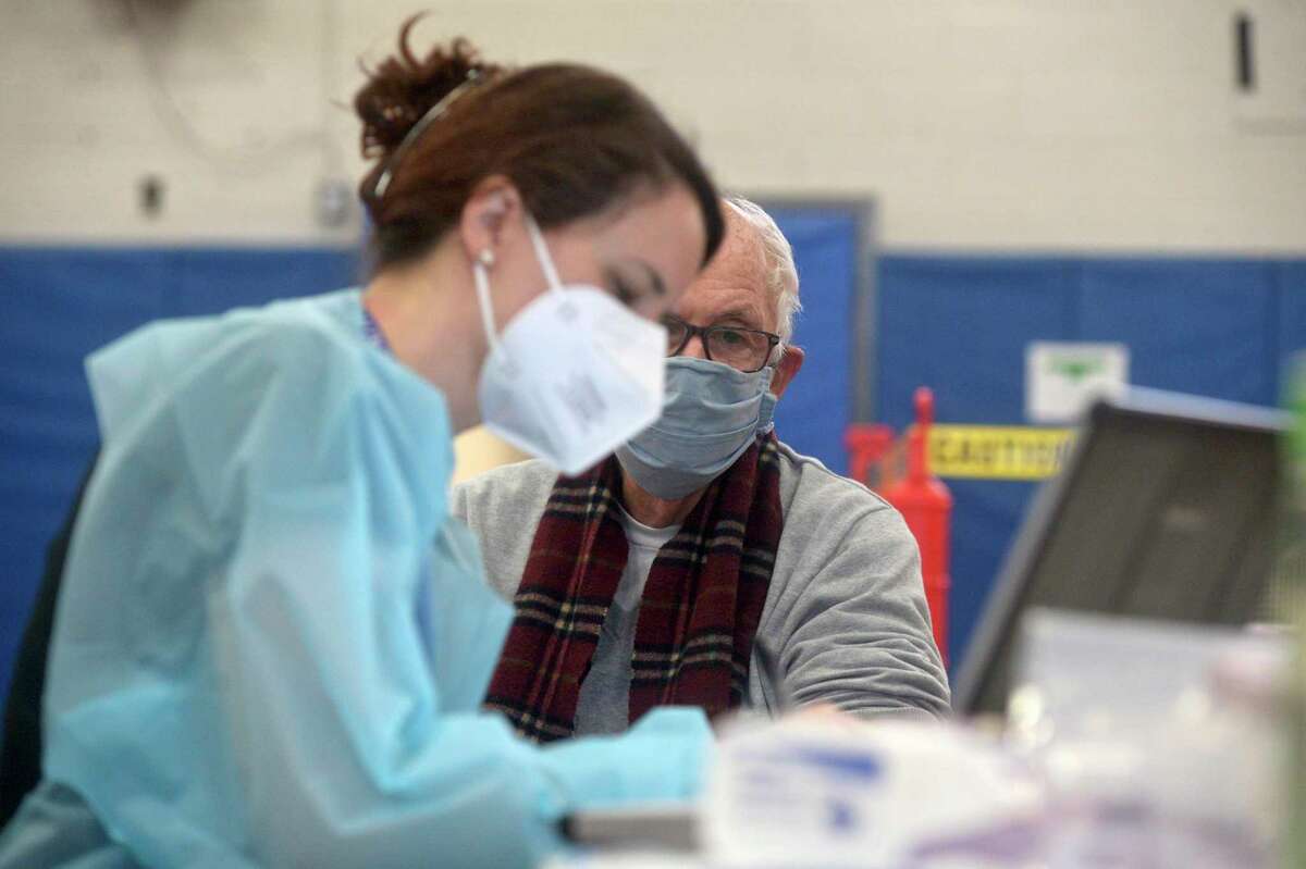 Bridget Bethray RN, with RVNAhealth takes information before administering a COVID-19 vaccine to Sherwin Gorenstein, of Ridgefield, in the RVNA clinic in the Yanity Gym, on Thursday morning, February 4, 2021, in Ridgefield, Conn.
