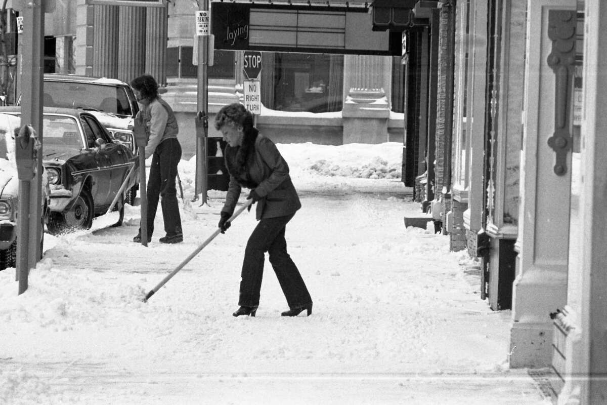 Shown here are two people shoveling snow on River Street near the corner of Poplar Street in early February 1981. (Manistee County Historical Museum photo)