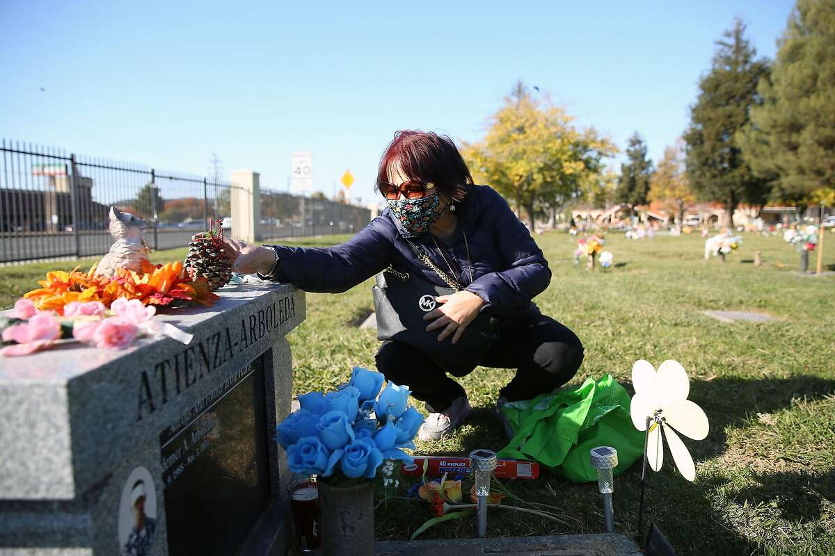 Jeannie Arboleda, mother of Laudemer Arboleda, decorates the headstone of her son Laudemer Arboleda with Christmas themed decorations during a visit to his grave site in the Sunrise Gardens at Chapel of the Chimes on Monday, November 30, 2020 in Hayward, Calif. Laudemer Arboleda was shot to death by a Danville police officer through the passenger window of his car while he was attempting to flee the police, unarmed and not accused of anything at the intersection of Diablo Road and Front Street in Danville, in 2018.