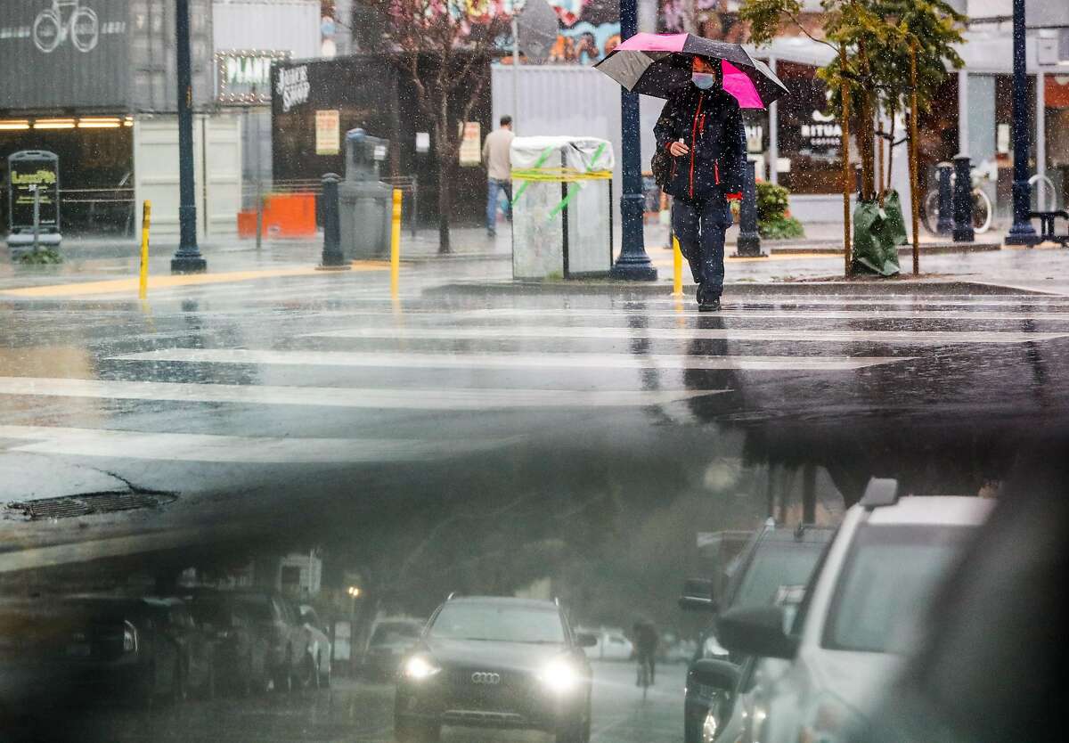 A woman walks through a rainstorm in Hayes Valley on Thursday, Feb. 11, 2021 in San Francisco, California.