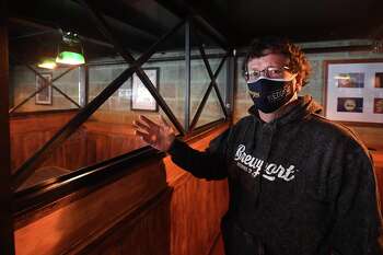 Senior partner Jeff Browning shows glass partitions added between booths, one of several indoor COVID-19 protections at Brewport in Bridgeport on Thursday. The restaurant has applied to the city for permanent outdoor dining.