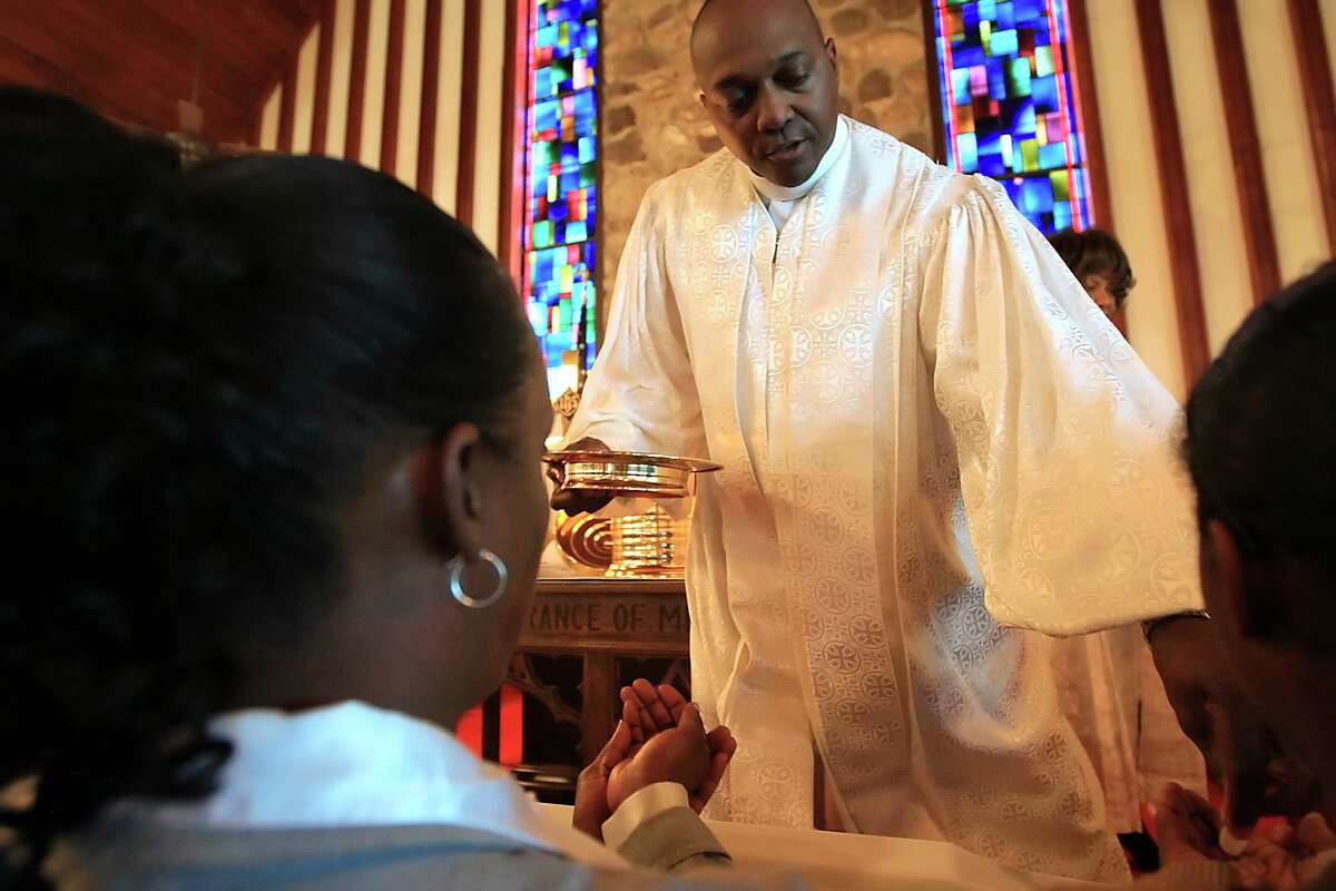 Rev. Dr. Raymond Bryant hands out communion at Bethel AME church in 2009. The church elder is named in a lawsuit by three trustees of Emmanuel AME Church.