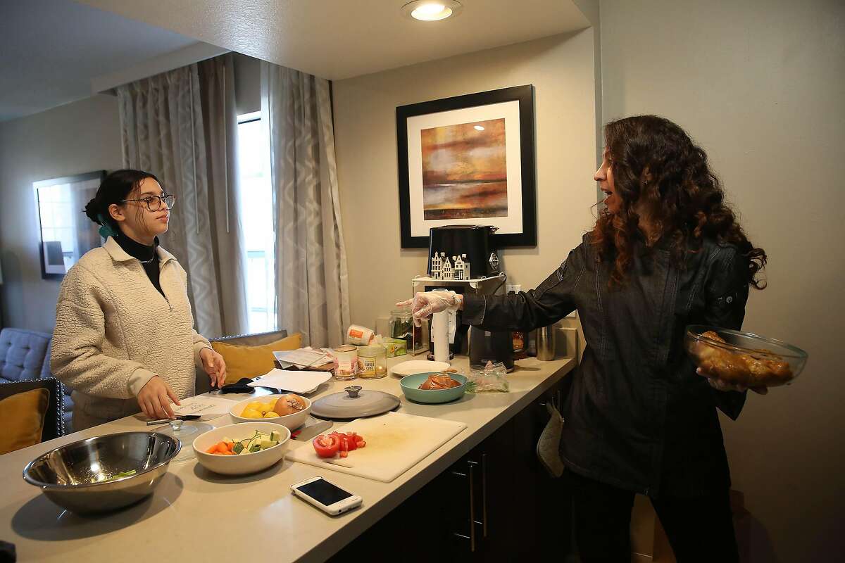Shereen Hassan-Aly (right) talks with her daughter Heba Hadi (left) as she cooks in a space she uses as a test kitchen and Hadi writes personalized notes for customized packaging on orders in a space she uses as a test kitchen on Friday, February 12, 2021 in Newark, Calif.