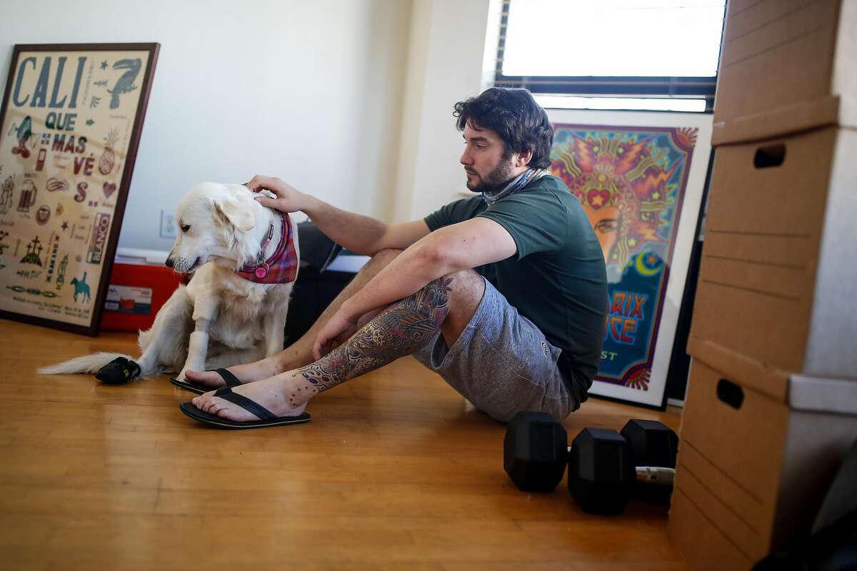 Kieran Blubaugh takes a moment to sit with his dog, Julia, as he packs up his apartment and prepares for his move to Texas on Friday, February 12, 2021 in San Francisco, Calif.