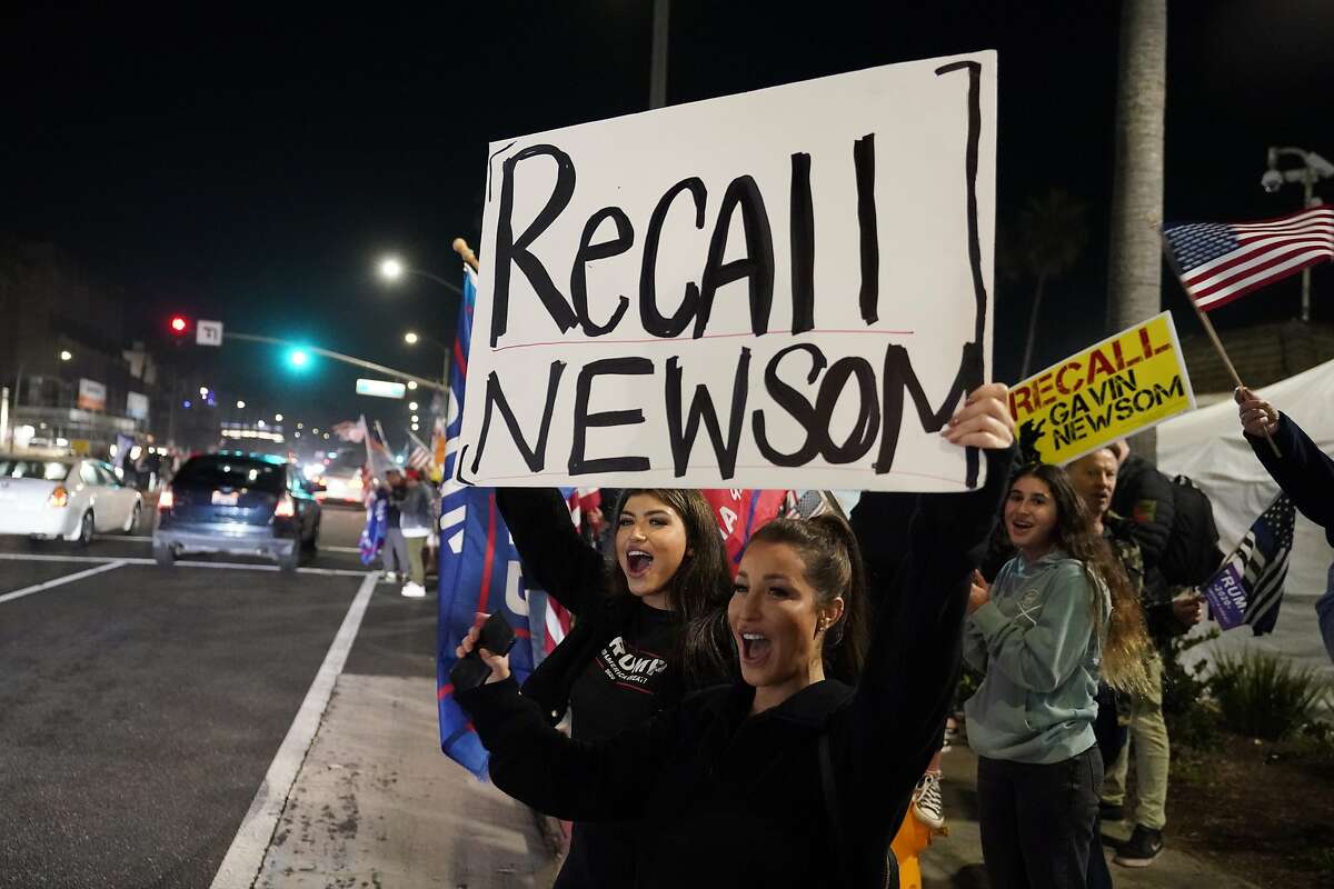 FILE — In this Nov. 21, 2020 file photo, demonstrators shout slogans while carrying a sign calling for the recall of Gov. Gavin Newsom during a protest against a stay-at-home order amid the COVID-19 pandemic in Huntington Beach, Calif. About a year after the state's first coronavirus case, Newsom has gone from a governor widely hailed for his swift response to a leader facing criticism from all angles. (AP Photo/Marcio Jose Sanchez, File)